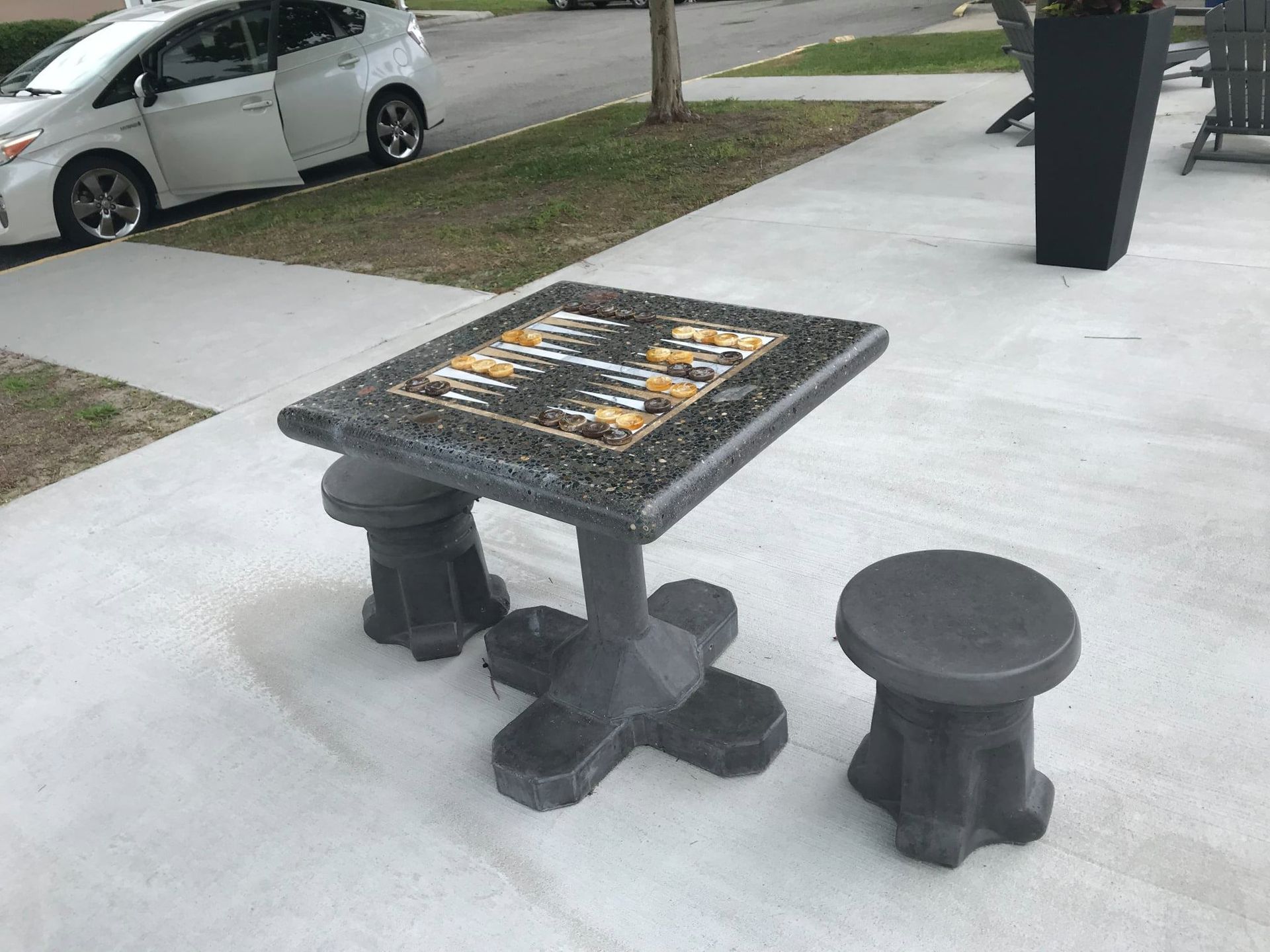 Freestanding Concrete Backgammon Table with Polished Aggregate Finish Freestanding outdoor concrete backgammon table with marble inlay in a public park.